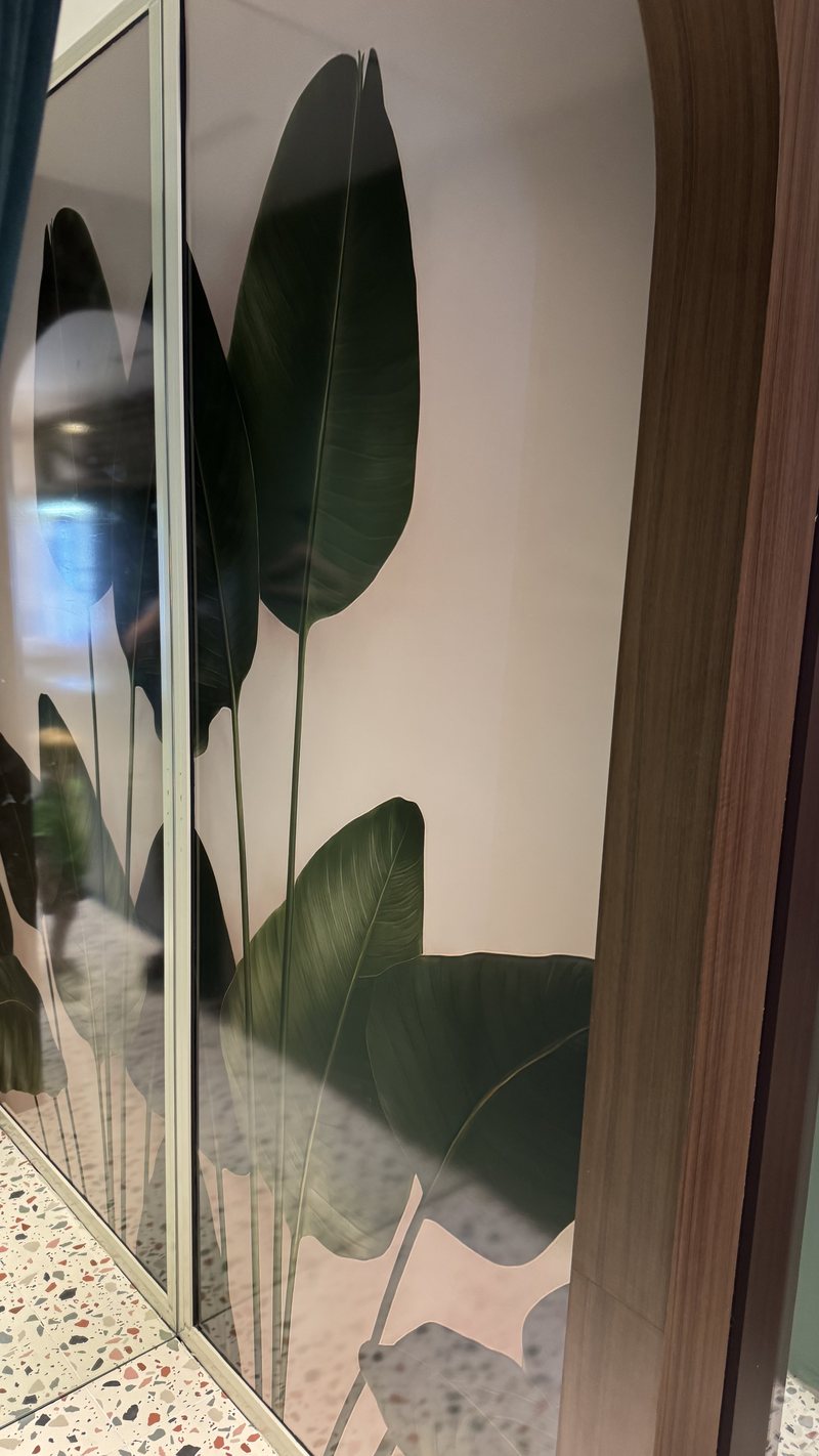 Installed botanical wall graphics viewed beside ribbed glass at the Padel Club
